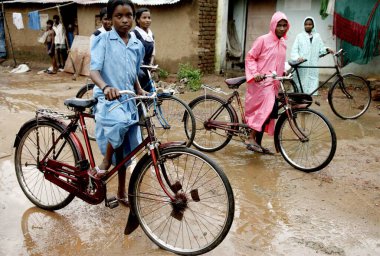 Çamurlu yolda bisiklet süren çocuklar, Bhubaneswar, Orissa, Hindistan 