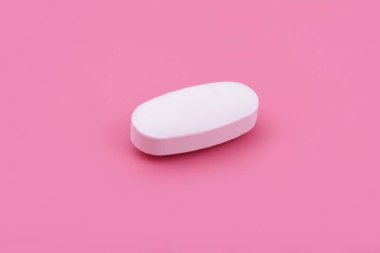 Pembe arka planda beyaz ilaç tableti