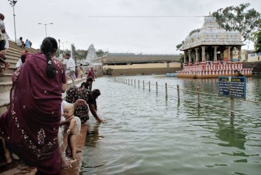 Devotees bathing the sacred tank Pushkarini at Tirumalai, Tirupati, Andhra Pradesh, India  clipart