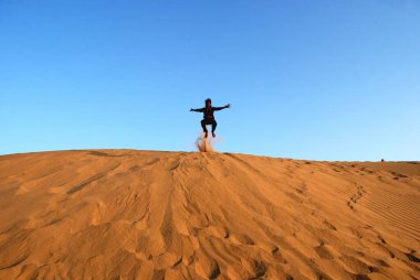 Kum tepesinin üzerinden atlayan çocuk, Khuri Khuhri, Jaisalmer, Rajasthan, Hindistan 