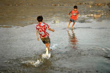 Sahildeki deniz suyunda oynayan iki Hintli çocuk; Bombay şimdi Mumbai, Maharashtra; Hindistan 
