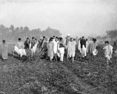 Köylüler ve iş arkadaşları eşliğinde Mahatma Gandhi Noakhali, Batı Bengal, Hindistan, Aralık 1946 'da yürür.   