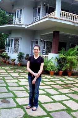 Panvel, New Bombay Mumbai, Maharashtra, Hindistan 'daki Varun çiftlik evinde gülümseyen ve siyah t-shirt ve kot pantolon giyen genç kız model. 
