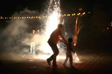 Baba ve oğul, Bombay Mumbai 'de, Maharashtra' da, Hindistan 'da, Diwali Deepawali' yi kutlarken ateş krakerleri patlatıyor.