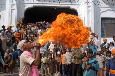 Man performing art of blowing fire from his mouth at Baba Bakala, a small town in the Amritsar district of Punjab on the occasion of the birth anniversary of Sikhs first guru Sri Guru Nanak Dev ji in Punjab, India  clipart