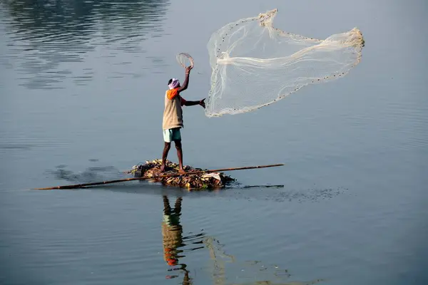 stock image A fisherman from the Haripur village on a makeshift boat throwing his net to catch fish in Krishna river in Sangli district ; Maharashtra ; India