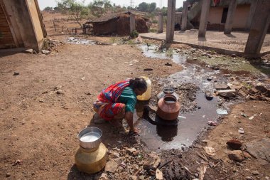 Su birikintisinden su toplayan kadın, Shahapur, Mumbai, Maharashtra, Hindistan, Asya 