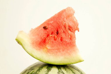 Fruits ; Watermelon cut into quarter piece showing red watery pulp with black seeds placed above one full melon ; Pune ; Maharashtra ; India clipart