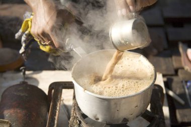 Çay satıcısı Hindistan 'da fincandan çaydanlığa buğulanmış çay dolduruyor.
