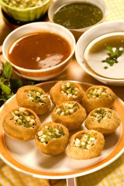 Atıştırmalık, pani puri ve lahana filizli turşu tabakta servis edilir. 