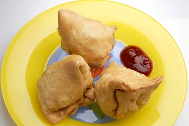 Hint usulü kızarmış yemek, samosa patatesi. Üç parçayı ketçapla dolduruyor.
