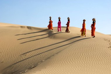 Khuhri, Jaisalmer, Rajasthan, Hindistan çöllerinde yürüyen kafası toprak kaplı kadınlar. 