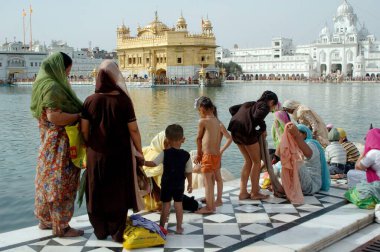 Sikh devotees take a holy dip in  Amrit sarovar the lake of nectar, Golden temple, Amritsar, Punjab, India  clipart