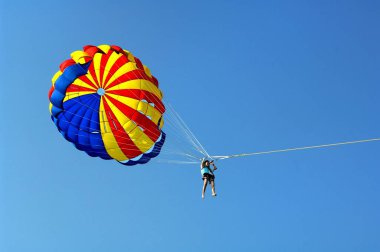 Mavi gökyüzüne karşı renkli paraşütle uçan kişi. Pattaya. Tayland 