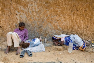 Öğle yemeği molasından sonra kızlarıyla birlikte Hindistan, Gujarat, Ahmedabad 'ın gölgesinin altındaki şantiyede kestiriyorlar. 