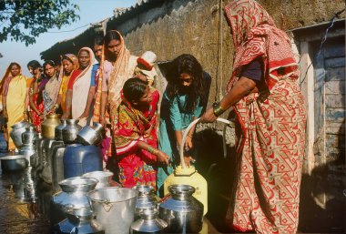 Kadınlar, Mumbai Bombay, Hindistan 'daki bir musluktan günlük su almak için gemileriyle gecekonduda kuyruğa giriyorlar. 