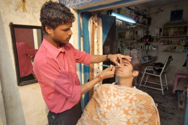 Taj saç ve güzellik salonunda sakalını kestiren genç bir adam, Dehradun, Uttaranchal, Hindistan 