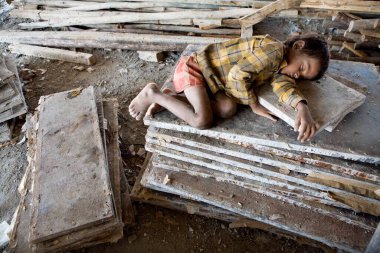 Ahmedabad, Gujarat, Hindistan 'daki inşaat malzemelerinin arasında uyuyan genç çocuk.  