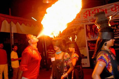 Girl covered eyes and man blowing fire on Navaratri festival ; Rajkot ; Gujarat ; India  clipart