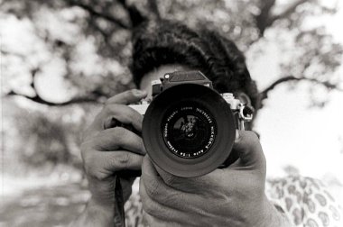 Elinde fotoğraf makinesi olan bir fotoğrafçının siyah beyaz fotoğrafı.