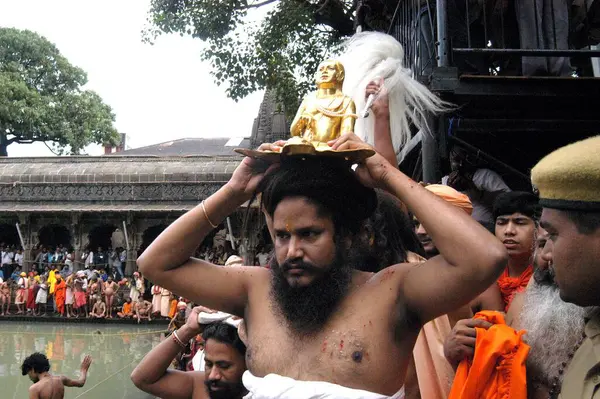 Dindarlar gurularının putunu başlarının üzerinde taşırken, Hindistan 'ın Maharashtra kenti yakınlarındaki Trimbakeshwar' da Kumbh Mela 2003 'te kutsal bir dalış yaptılar.. 