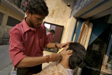 Taj saç ve güzellik salonunda sakalını kestiren genç bir adam, Dehradun, Uttaranchal, Hindistan.