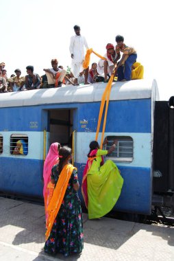 Erkekler kadını tren istasyonunun çatısında türbanla sürüklüyor. Jodhpur, Rajasthan, Hindistan. 