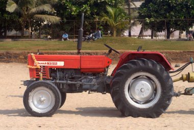 HMT 7511 'in kırmızı renkli traktörü Juhu sahilinde, Bombay Mumbai, Maharashtra, Hindistan 