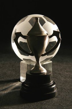 Camdan yapılmış küçük metal kupa ve futbol topu veya futbol sporu