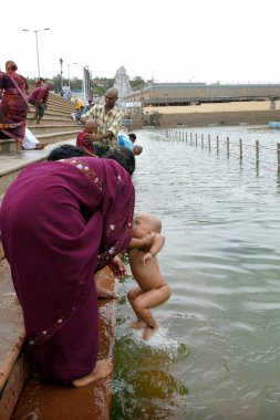Devotees bathing the sacred tank Pushkarini at Tirumalai, Tirupati, Andhra Pradesh, India  clipart