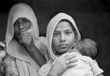 Hindistan, Rajasthan kırsalının arkasında duran çocuğu ve büyükannesiyle birlikte genç bir anne. 