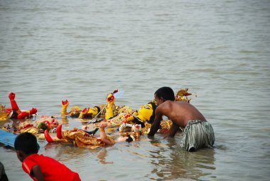 Devotees immersing Durga model in river  clipart