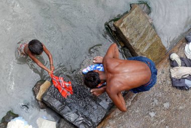 Çamaşırcı, Bombay, Maharashtra, Hindistan 'da Dharavi' de çocuğuyla birlikte kirli sularda çamaşır yıkıyor. 