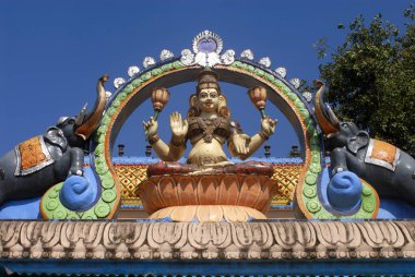 Colourfully painted Goddess Lakshmi sitting on lotus with elephants on both sides on facade of Shree Durga Parmeshwari Temple at Kateel, Dakshina Kannada District, Karnataka, India  clipart