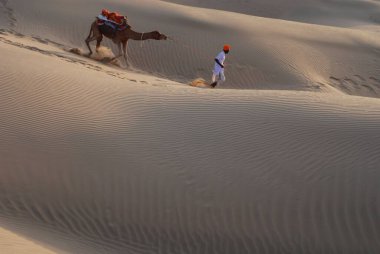 Kune, Khuri, Jaisalmer, Rajasthan, Hindistan 'dan geçen develi adam. 