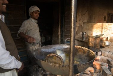 Rosogollas 'ta kızaran bir adam. Şeker suyunda haşlanmış un topları. Mandawa, Rajasthan, Hindistan. 