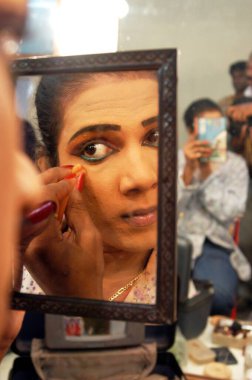 Erkek sanatçı göz kalemi kullanıyor. Bin Baicha Tamasha, Hindistan gösterisine hazırlanıyor.   