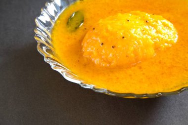 Yiyecek, mango körisi siyah arka planda kasede servis edilir.  