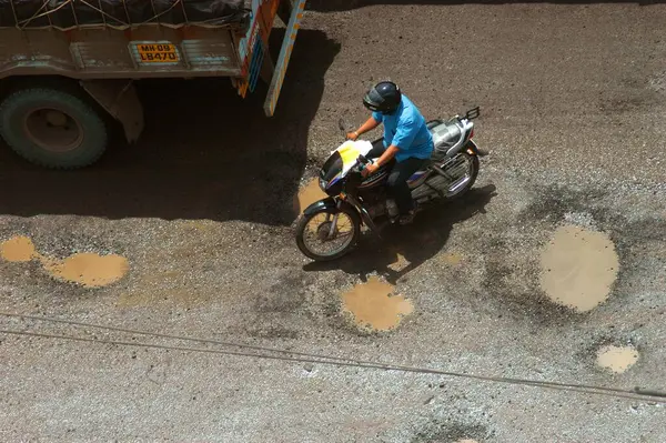 Stock image Two wheelers and heavy vehicles take treacherous journey in monsoon on Ghodbunder road in Thane, Maharashtra, India 