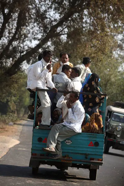 stock image Group of people travelling sitting behind three wheeler scooter seen on highway towards Ahmedabad, Gujarat, India 