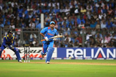 Hintli vurucu M S Dhoni atışını yaparken, Sri Lankalı kaptan, kale bekçisi Kumar Sangakkara Hindistan ile Sri Lanka arasındaki ICC Dünya Kupası finalinde 2 Nisan 2011 'de Mumbai' deki Wankhede Stadyumu 'nda seyrediyor.
