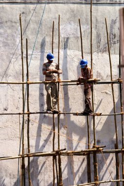 İnşaat işçileri, bambuları iple bağlıyorlar. 