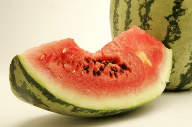 Fruits ; Cut piece of watermelon showing red watery pulp with black seeds against  one on white background ; Pune ; Maharashtra ; India clipart