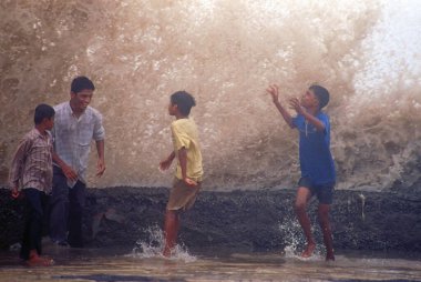 boys enjoying sea waves in monsoon season , bombay mumbai , maharashtra , india clipart