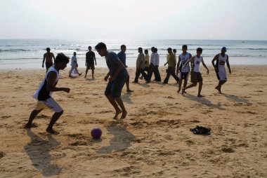 Tourists playing football at Candolim beach, Goa, India  clipart