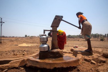El pompasından su pompalayan kabile kadını, Nandgaon, Atgaon, Maharashtra, Hindistan, Asya 