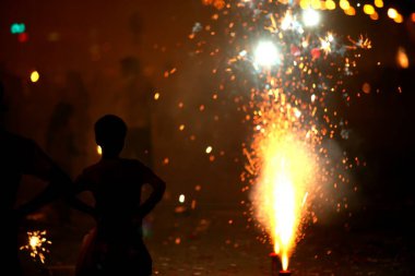 Bombay Mumbai 'de, Maharashtra' da, Hindistan 'da deniz hatlarında ateş krakerleri patlamasını izleyen genç çocuk.