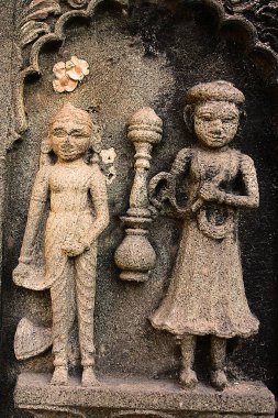 Indian couple, man with Hukka - Indias traditional tobacco pipe in hand, carved on the wall of Ahilayabai temple, ornamental carving on stone, old Indian sculpture, Heritage site, sculpture over wall, in a building on Ahilayabai ghat of Narm. clipart