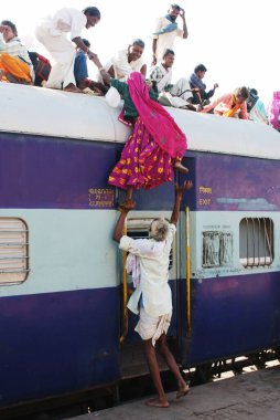 Tren istasyonunda, Jodhpur, Rajasthan, Hindistan 'da trenin çatısına tırmanmaya çalışan kadına yardım eden yaşlı adam. 