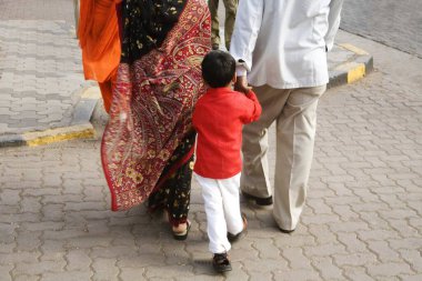 Ailesini takip eden kırmızı tişörtlü Hintli çocuk; Sanat Kurulumu; Kala Ghoda festivali 2008; Bombay şimdi Mumbai; Maharashtra; Hindistan;